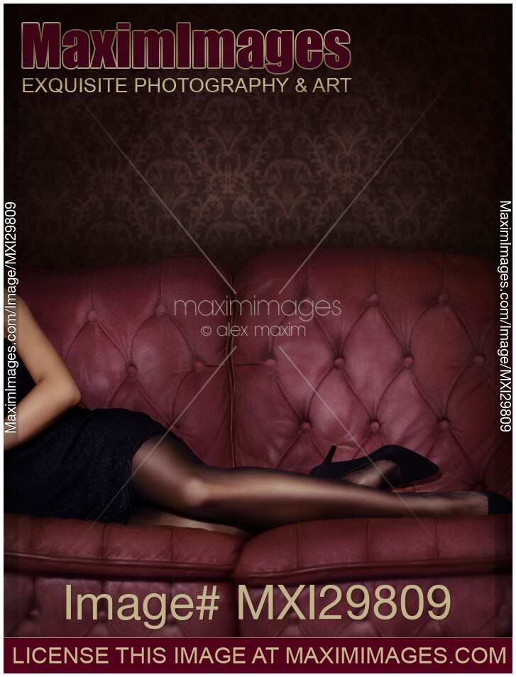 Closeup of sexy legs in black stocking of woman lying on luxurious dark pink tufted couch