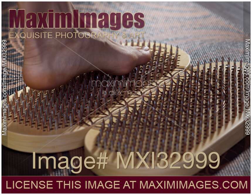 Closeup of woman foot standing on Yogic Sadhu Board of nails