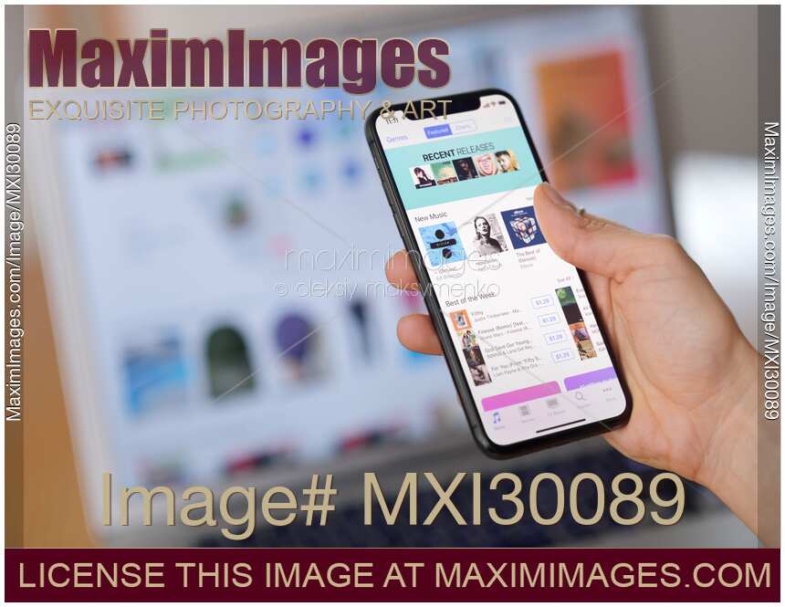 Closeup of woman hand with Apple iPhone X displaying iTunes store music on its screen
