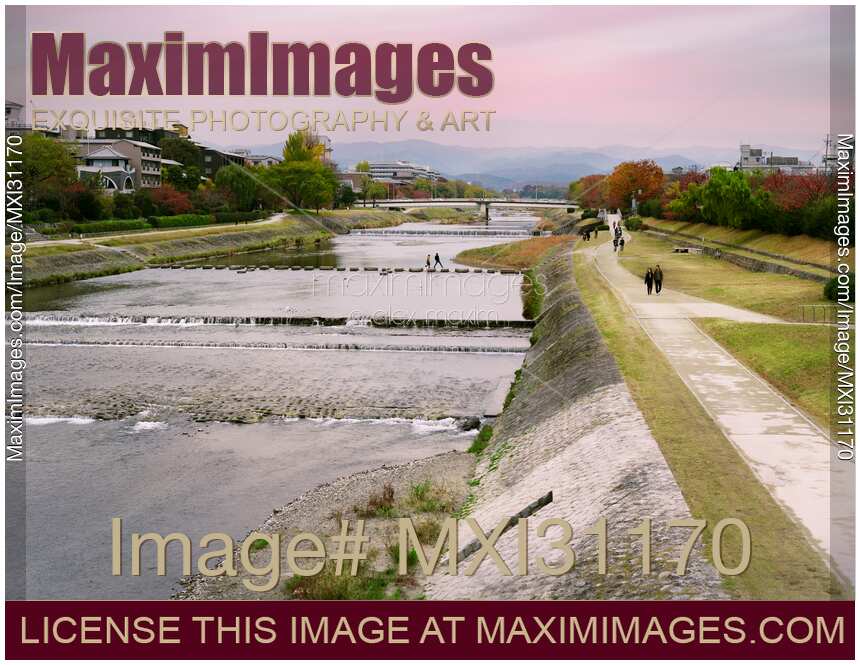 Couple crossing Kamo River by walking on stepping stones Kyoto city scenery