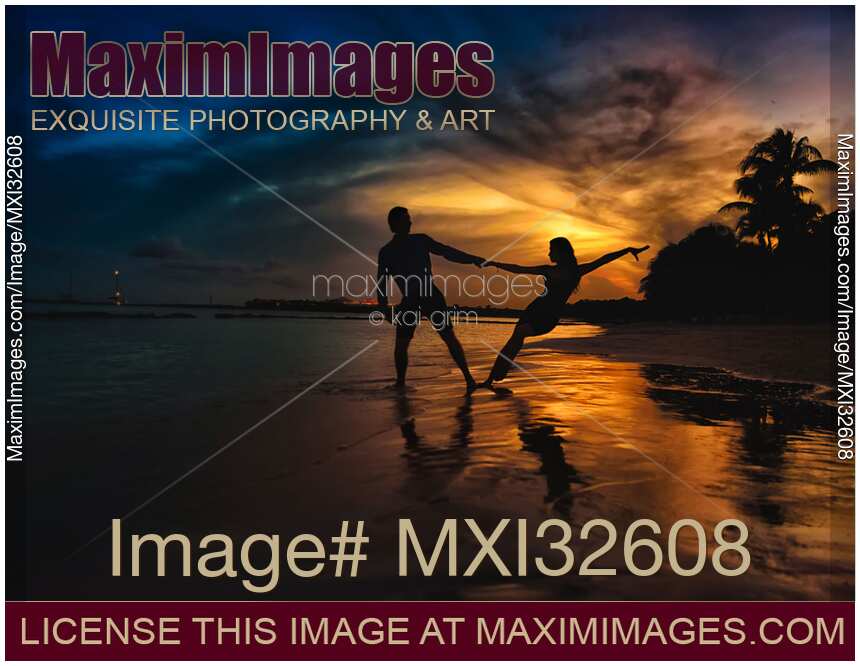 Couple dancing at a sea shore in sunset Man and woman dark silhouettes holding hands at the beach