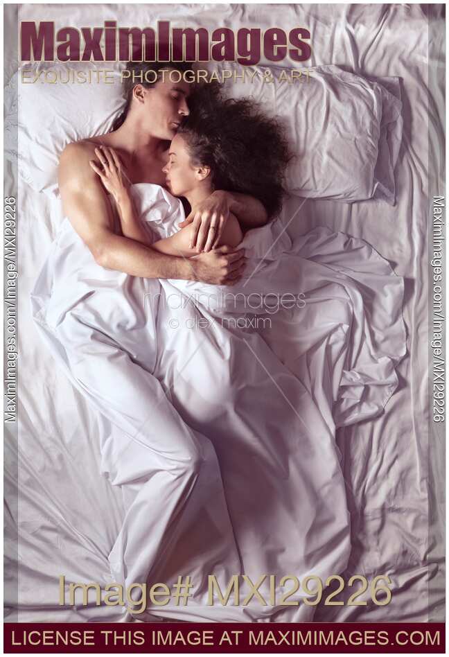 Couple sleeping together in bed in morning sunlight
