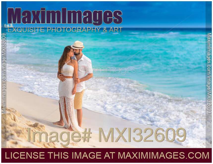Couple together in an embrace on a sunny sandy sea shore of a Caribbean Sea beach in Cancun Mexico