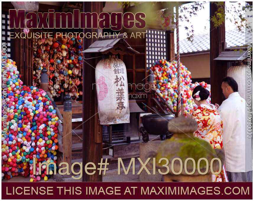 Couple wearing traditional kimonos praying at Yasaka Koshindo in Kyoto Japan