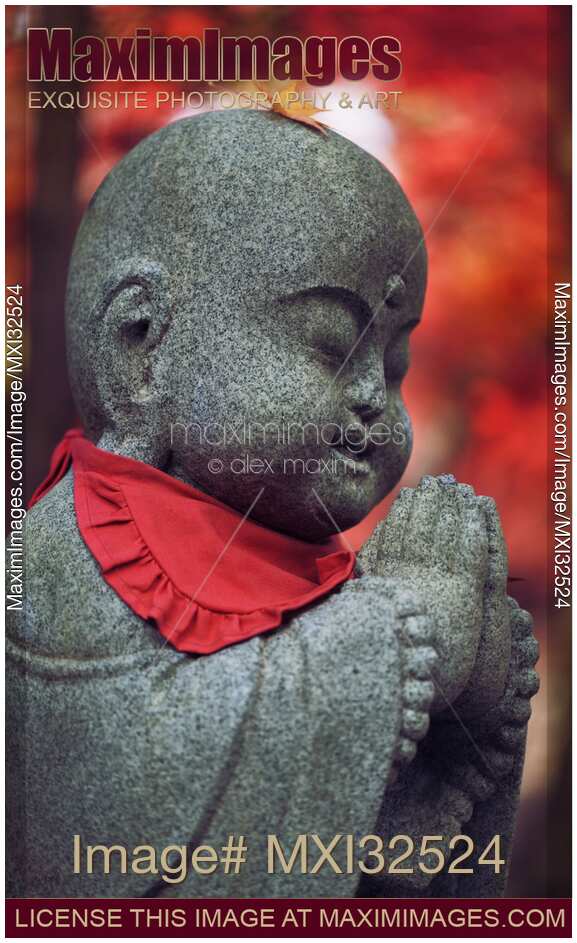 Cute Baby Buddha with a fallen maple leaf on his head stone statue in autumn scenery in Kyoto