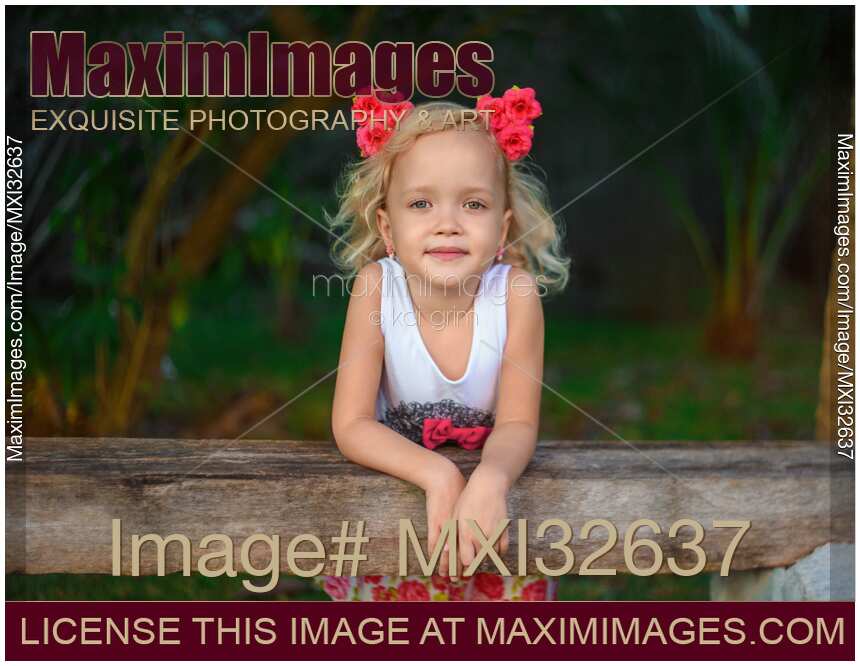 Cute smiling little girl with pink flowers in her blond hair