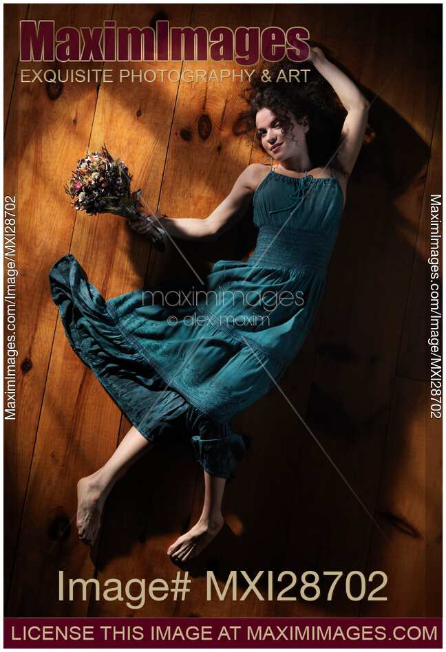 Cute smiling young woman in green dress lying on the floor