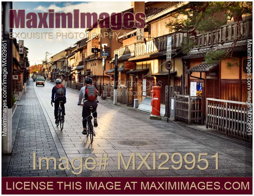 Cyclists on Hanamikoji Dori street in Gion district in the morning Kyoto Japan
