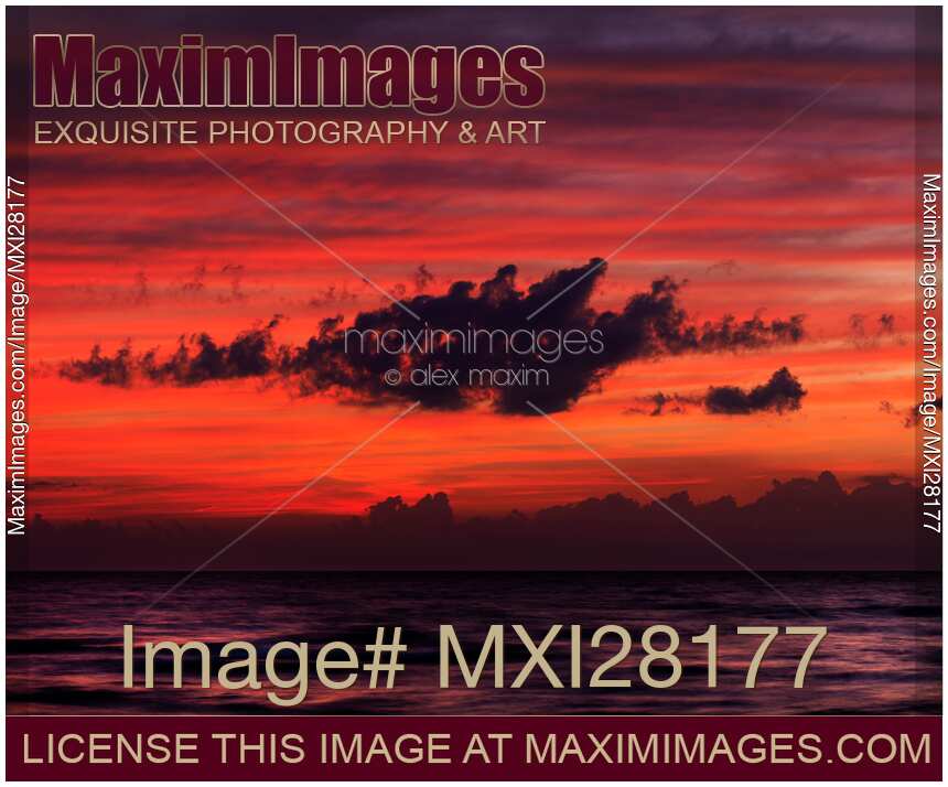 Dark dramatic clouds backlit by beautiful red sunset sky