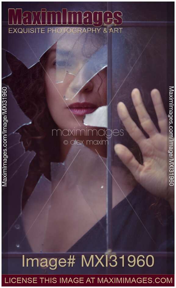 Dramatic conceptual portrait of a woman face behind a broken window pane glass