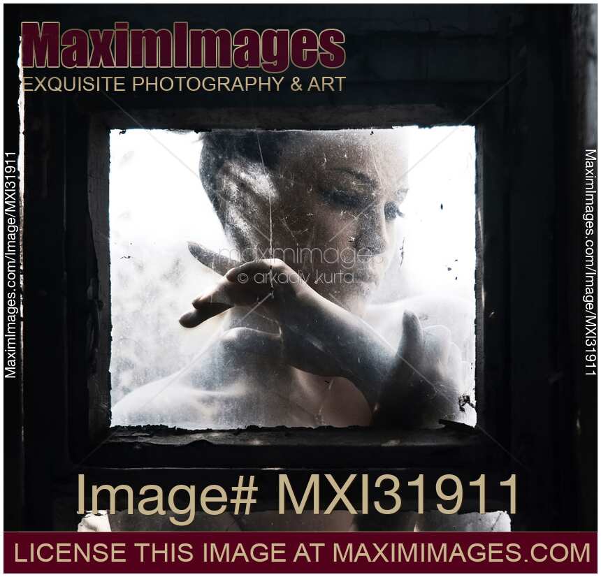 Dramatic expressive portrait of a woman face behind a closed dusty window glass