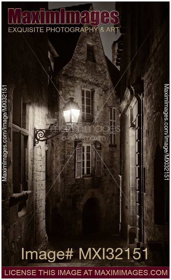 Dramatic fine art nighttime scenery of an old street lit by a lamp in a French medieval town