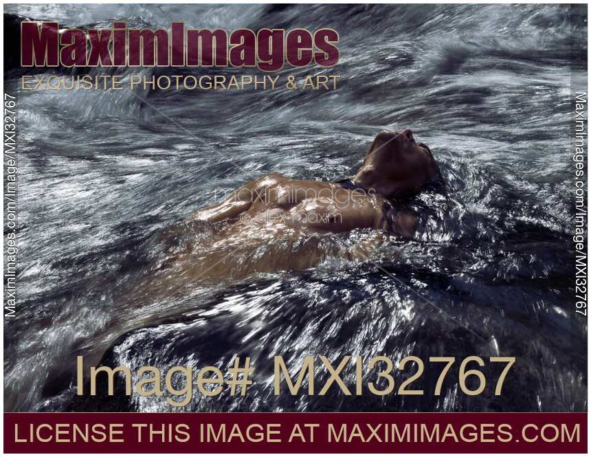 Dramatic portrait of a man with bare torso submerged in rushing river water