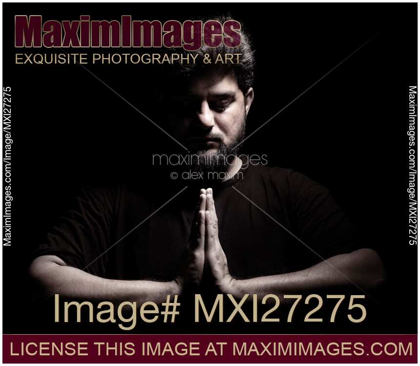 Dramatic portrait of a man with hands folded in prayer