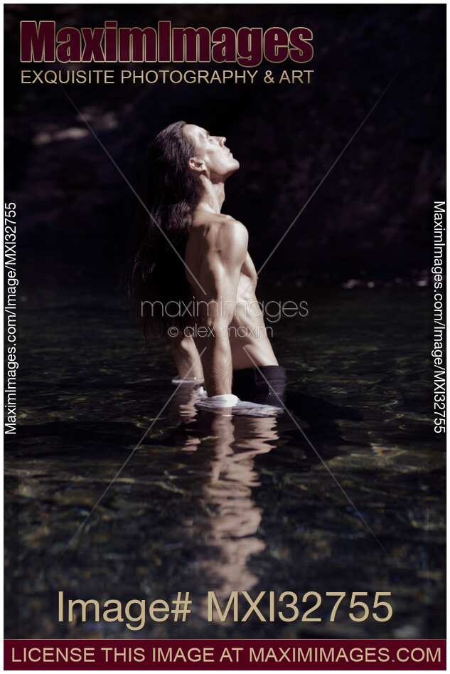 Dramatic portrait of a shirtless man with bare torso standing in water in pants