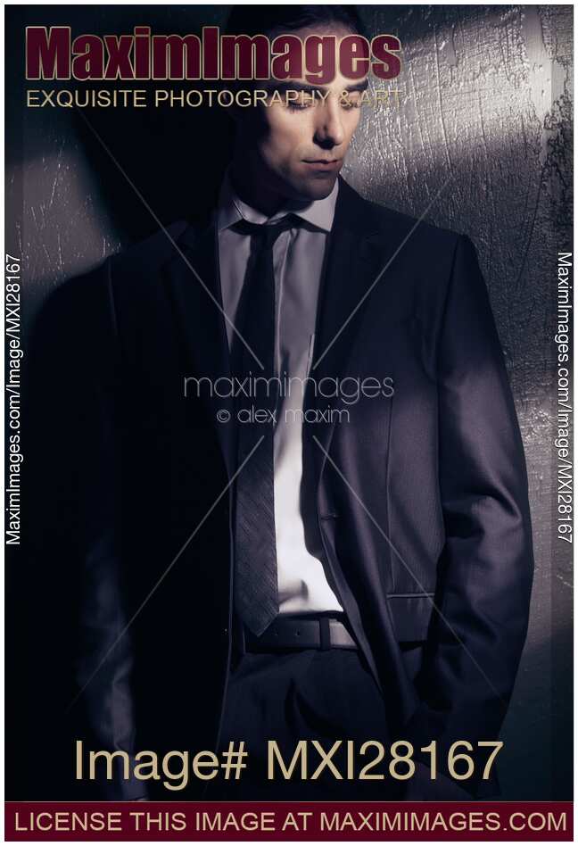 Dramatic portrait of man in black suit in dim light