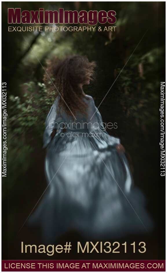 Dramatic rear view portrait of a woman running away into a deep dark forest