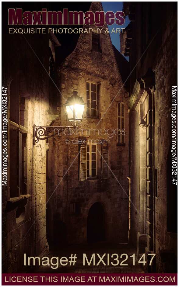Dramatic scenery of an old street lit by a lamp in a French medieval town at dusk