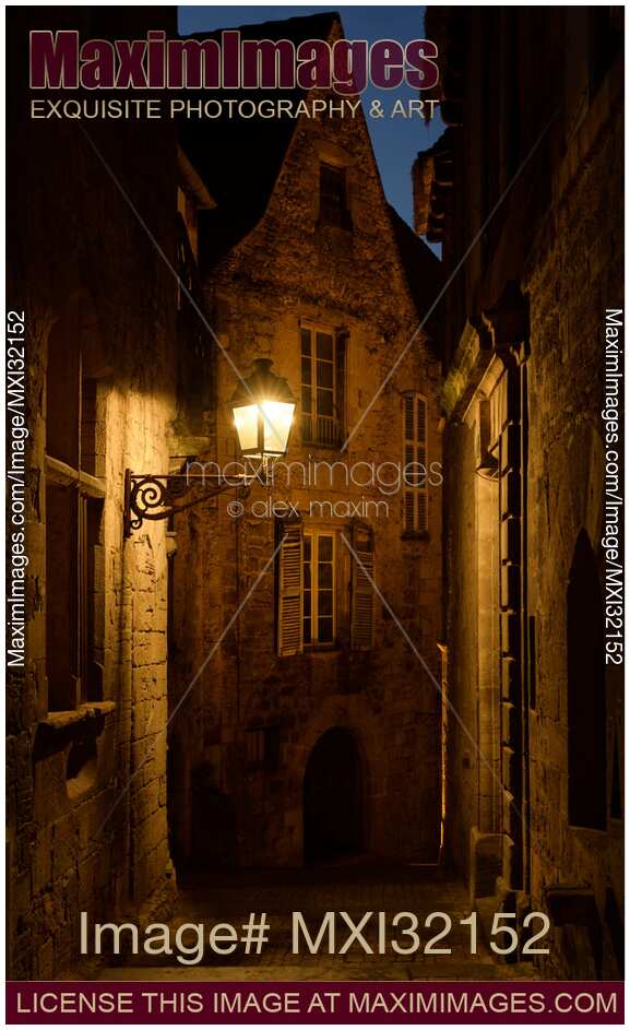Dramatic twilight scenery of an old French street with stone houses lit by a street lamp