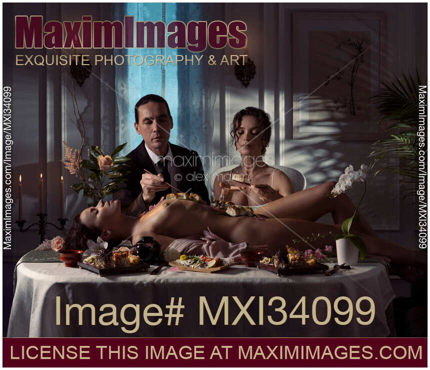 Elegant couple eating Nyotaimori sushi served on naked body of beautiful nude woman lying on restaurant table