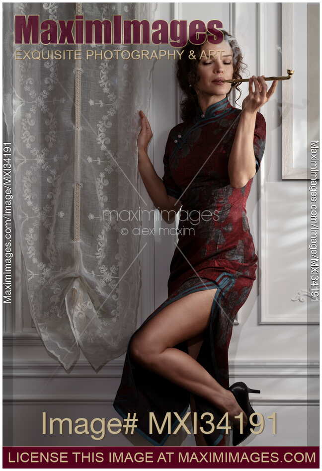 Elegant lady in Shanghai-style Cheongsam dress leaning against wall smoking long Chinese pipe