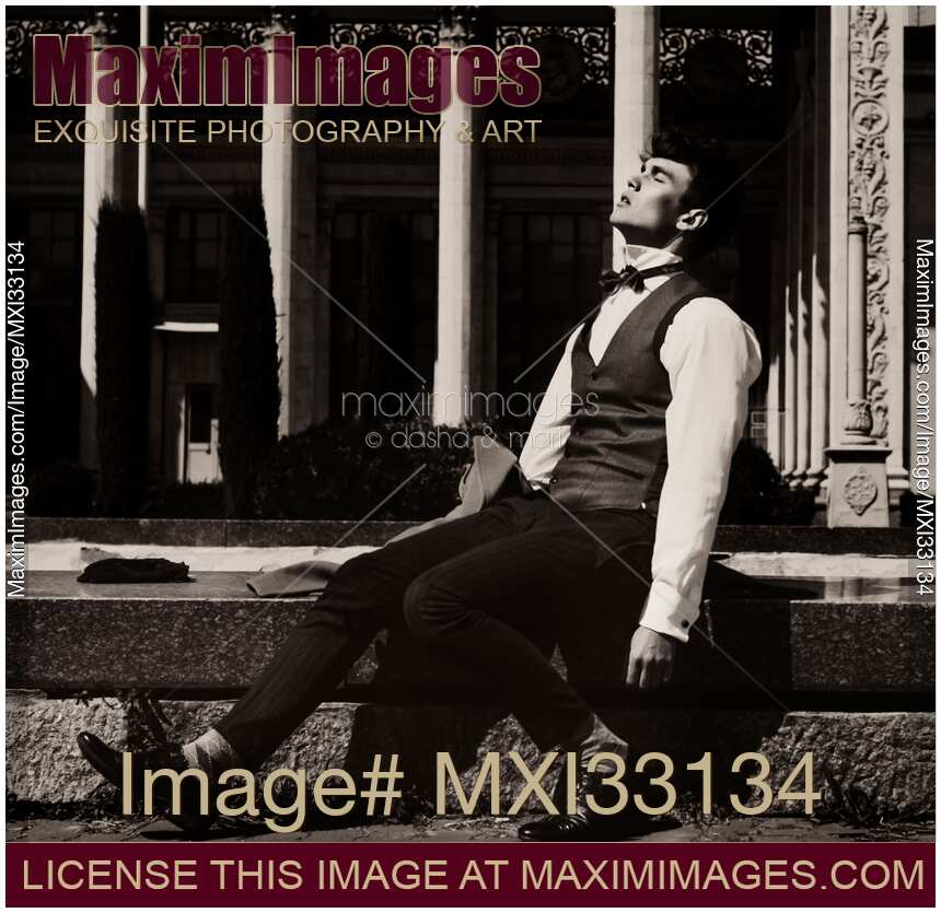 Elegantly dressed man sitting by a fountain taking a break enjoying the sunshine outdoors with abandon