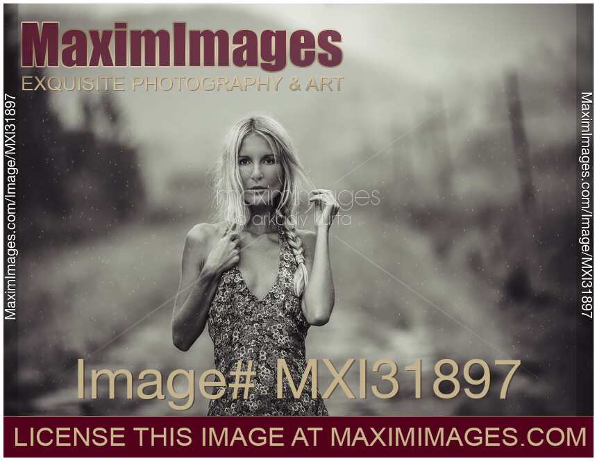 Expressive portrait of a blond woman in a summer dress standing on country road