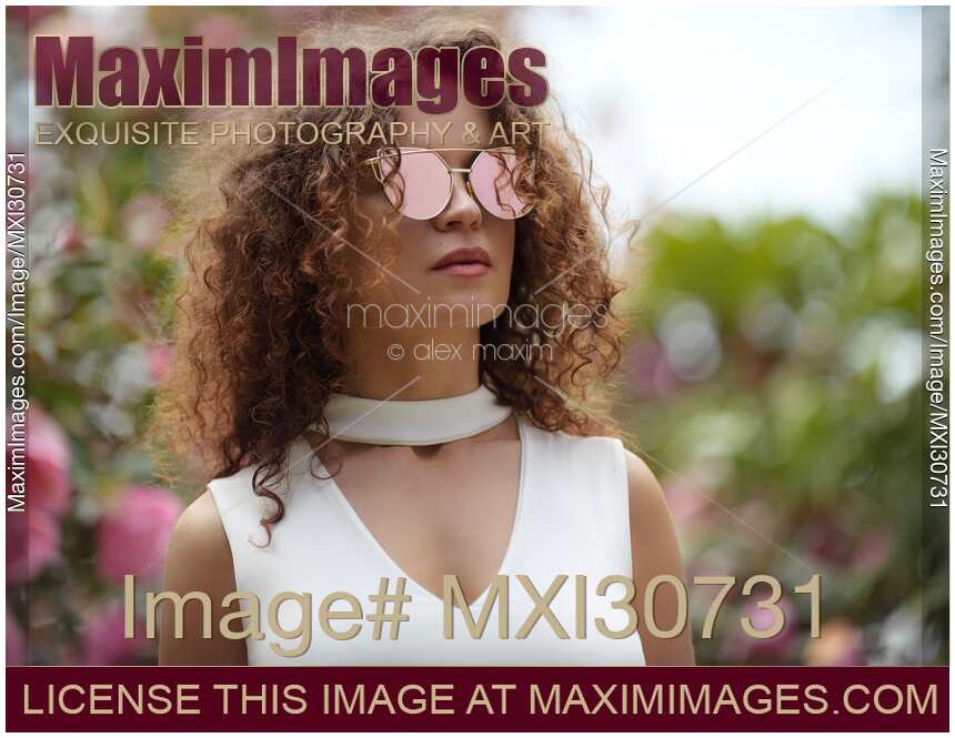 Fashion portrait of a beautiful young woman wearing cat-eye sunglasses and a white v-neck top