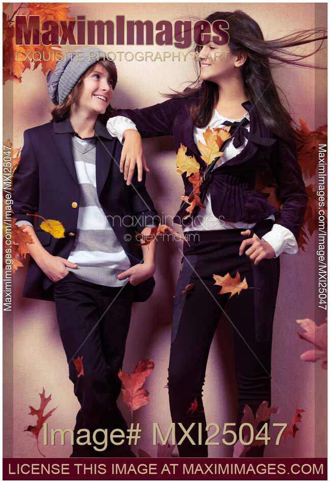 Fashionably dressed boy and teenage girl under falling autumn leaves