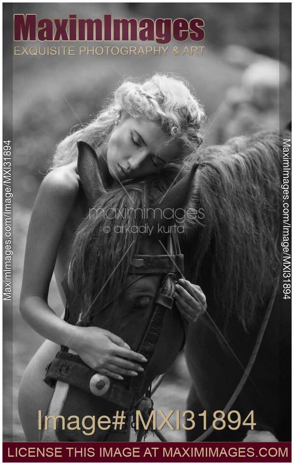Fine art black and white photograph of a naked woman hugging a horse in the forest