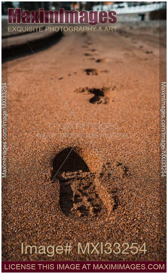 Footprints from running shoes along the sandy beach