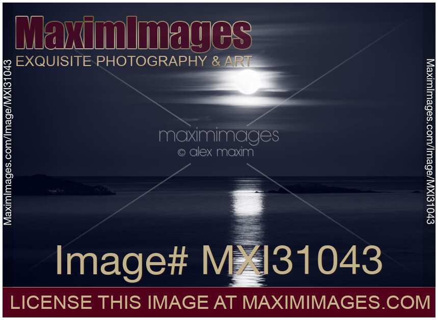 Full Harvest Moon rising above Pacific ocean in autumn Black and white