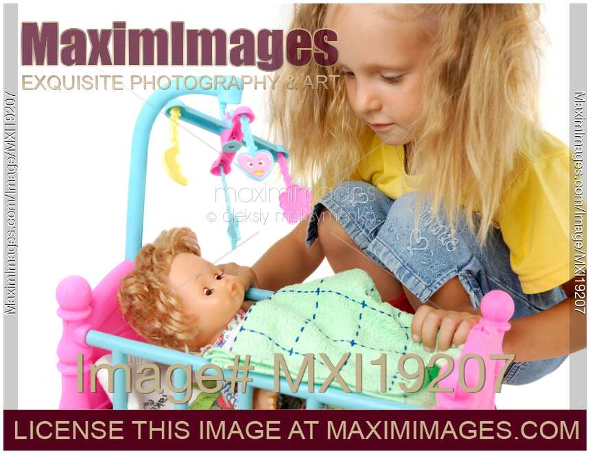 Stock photo Girl playing with baby doll and toy crib MaximImages