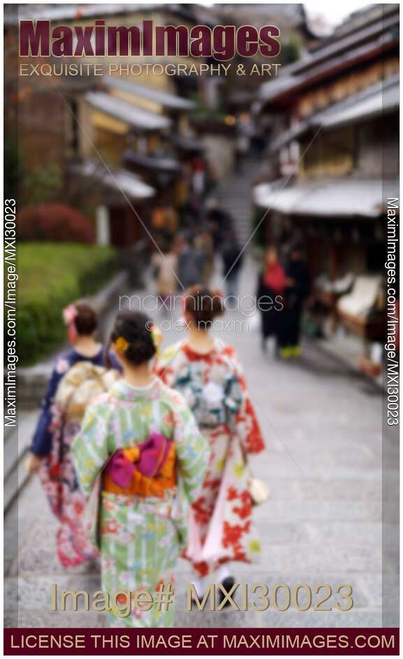 Girls in bright yukatas walking down an old street in Kyoto with artistic out-of-focus blur