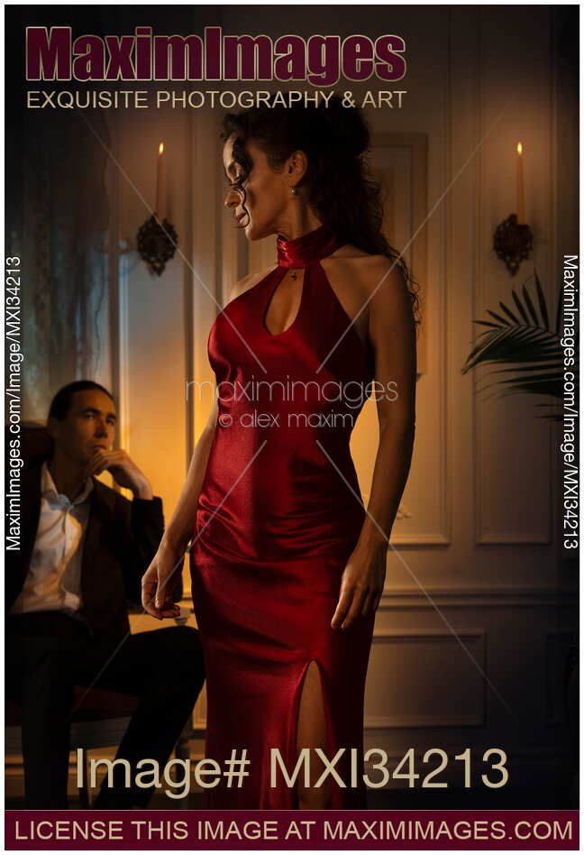 Gorgeous classy lady in sexy red dress walking past a man sitting a chair with a contemplative look