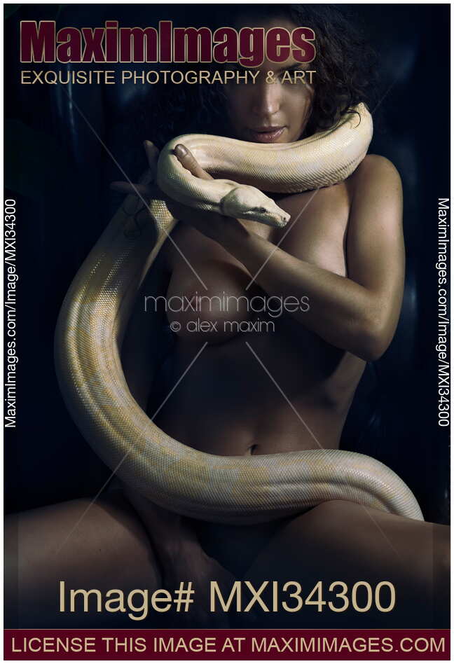 Gorgeous mysterious powerful woman with large white boa snake coiled around her sexy naked body in shadows