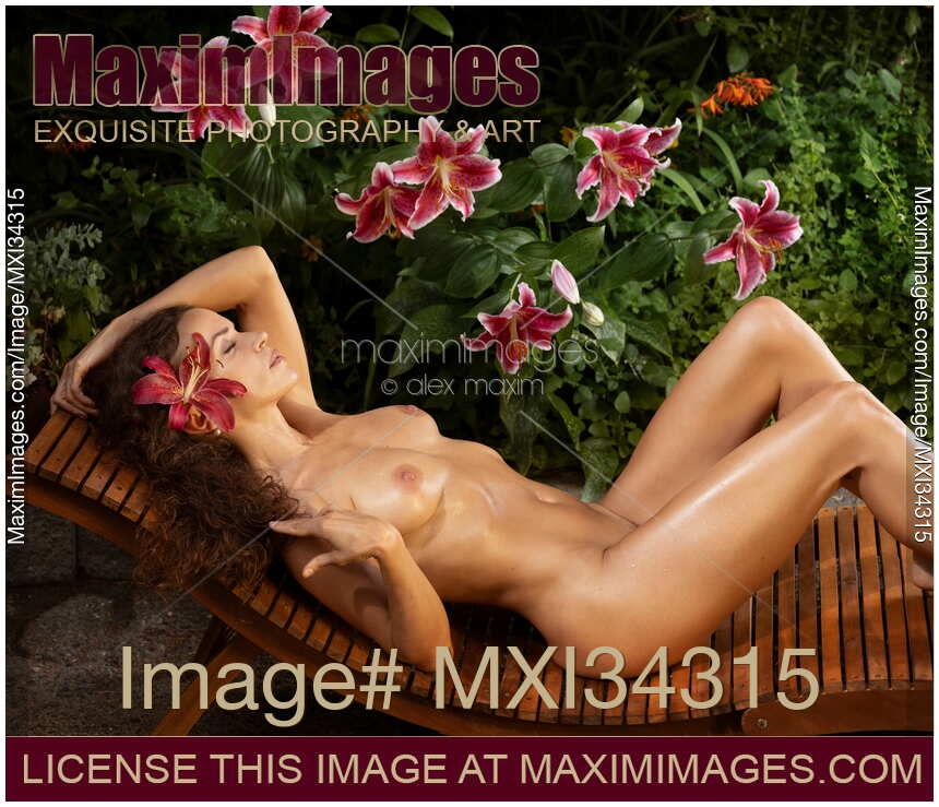 Gorgeous nude sexy woman with wet sun-tanned naked body lying on chaise lounge in sensual pose in lily garden