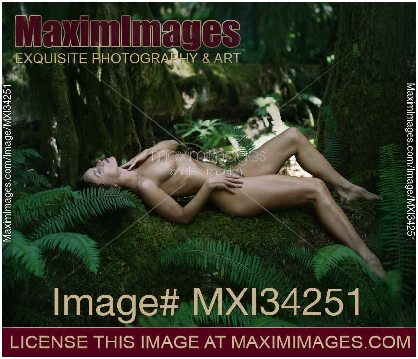 Gorgeous nude woman lying on green moss in dark forest nature scenery gently caressing herself