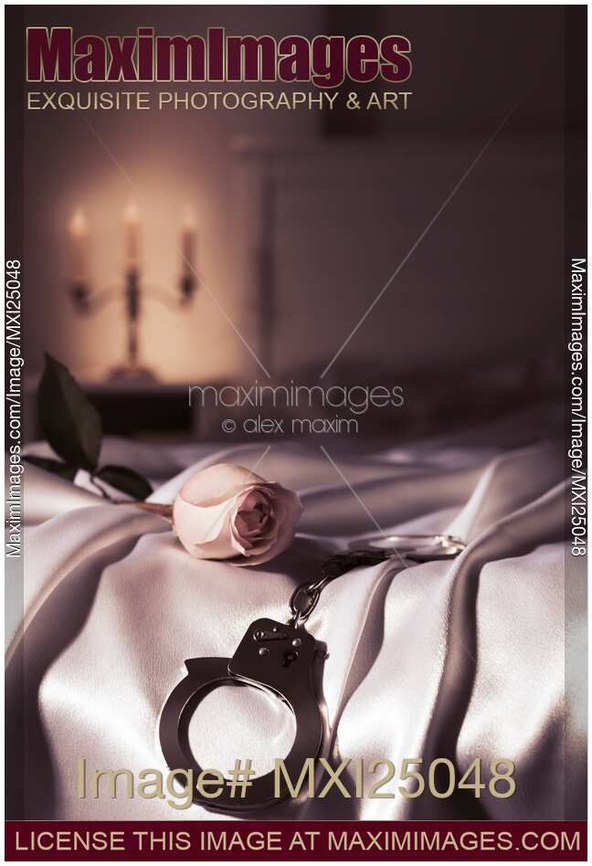 Handcuffs and a rose on bed Romantic suggestive still life