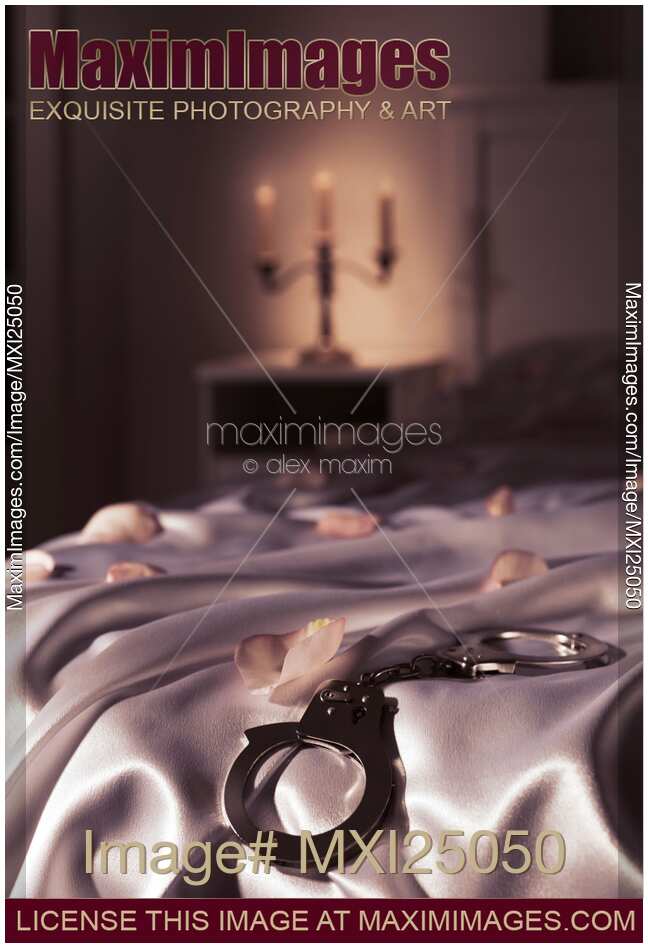 Handcuffs and rose petals on bed artistic suggestive bondage concept