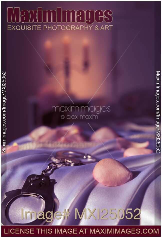Handcuffs ropes and rose petals on bed BDSM sex romantic concept