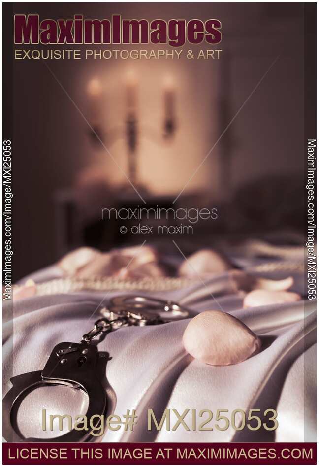 Handcuffs ropes and rose petals on bed BDSM sex romantic concept
