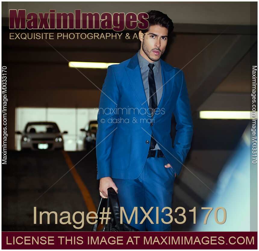 Handsome man in a classic elegant blue business suit walking to his car in indoor parking lot