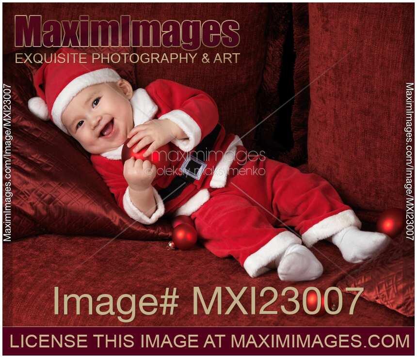 Happy Baby Boy in Santas Costume with a Christmas Bauble