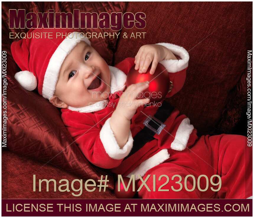 Happy Baby Boy in Santas Costume with a Christmas Bauble