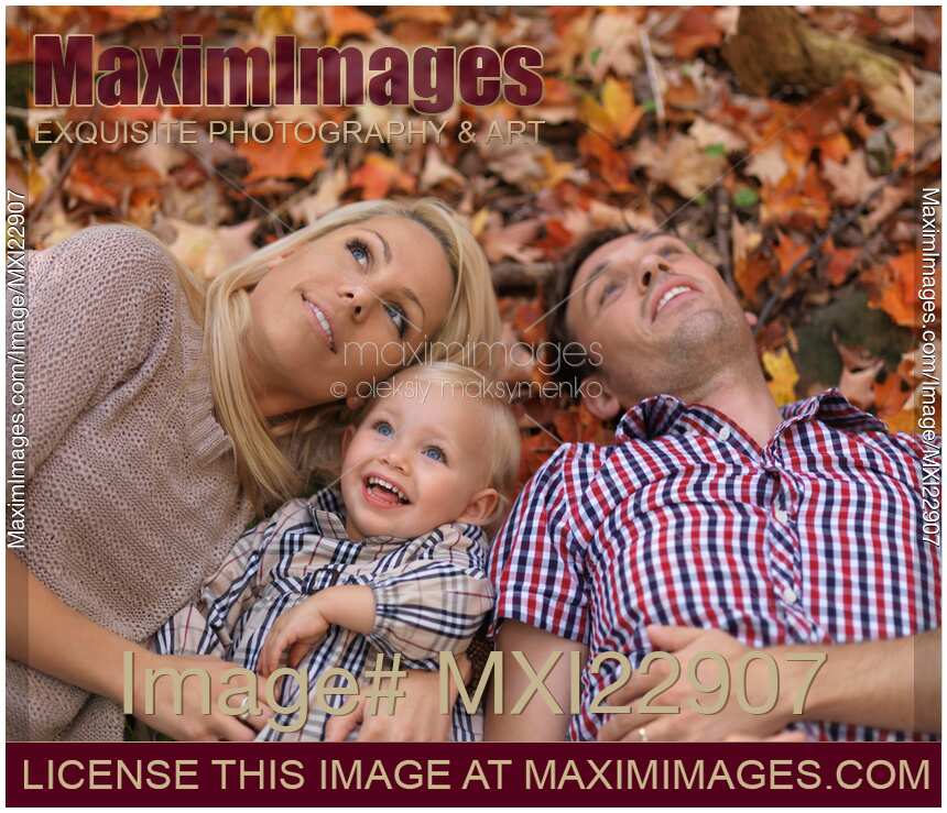 Happy Smiling Family Lying on Fallen Autumn Leaves