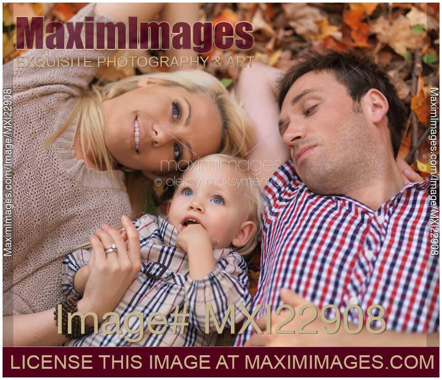 Happy Smiling Family Lying on Fallen Autumn Leaves