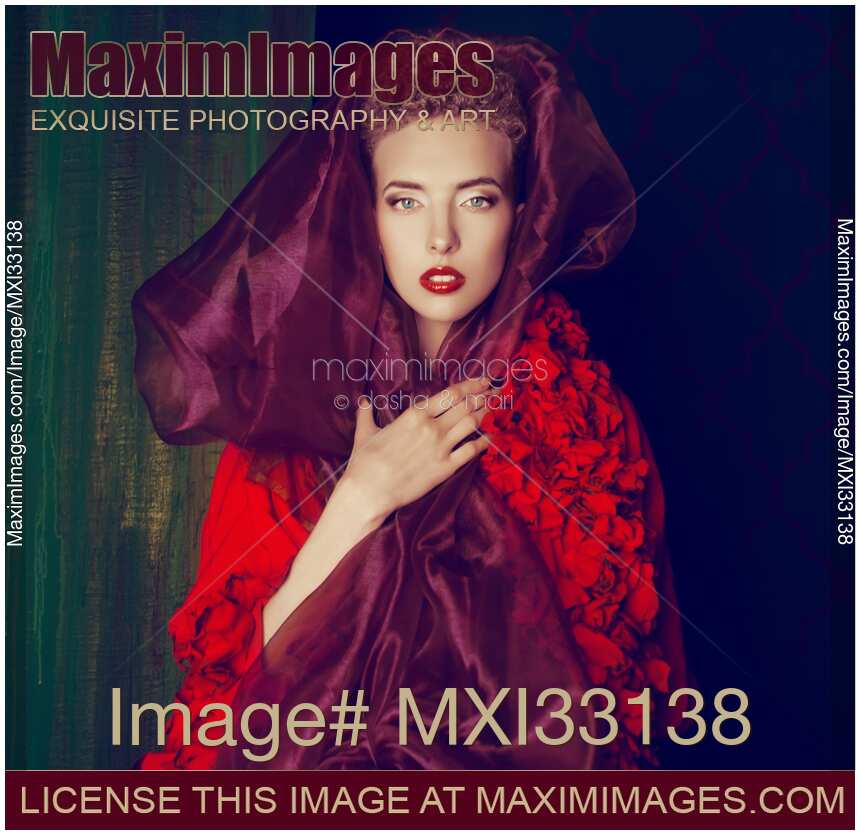 High fashion portrait of a red-haired woman wearing a purple shawl around her face and red lace dress