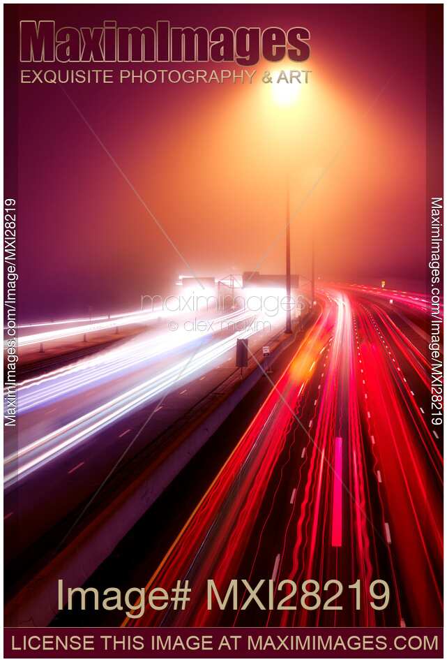 Highway traffic light trails in fog at nighttime