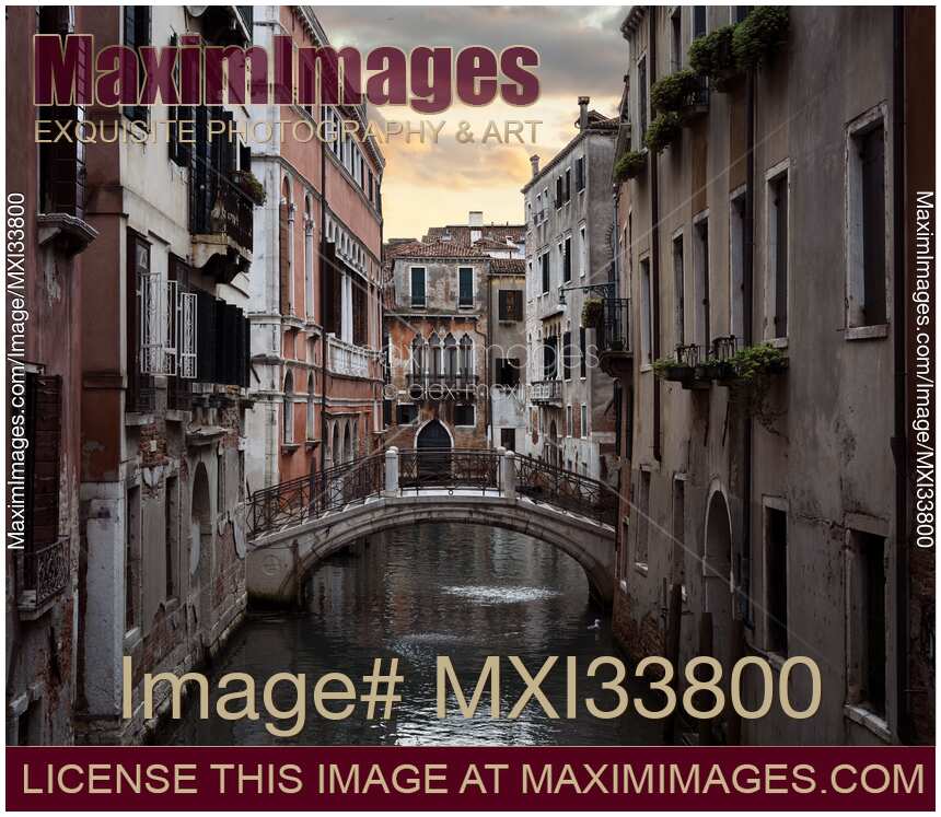 Historic old buildings and a foot bridge over a waterway at sunset in Venice Italy